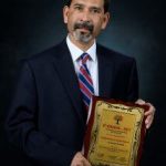 Suman Chandra holds award plaque