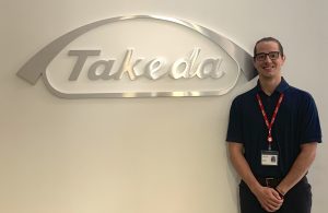 Austin Arnold standing next to the Takeda sign.